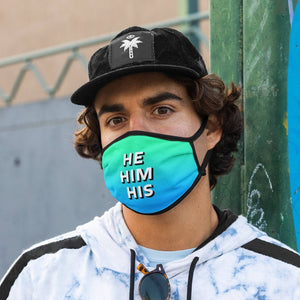 Man with brown curly hair wearing a green/blue gradient coloured face mask with HE HIM HIS pronouns on it.